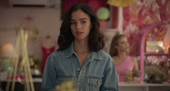 Movie still from “Along for the Ride” (2022), directed by Sofia Alvarez – A young woman in a denim jacket looking at the camera; Close Up shot, Over the shoulder angle