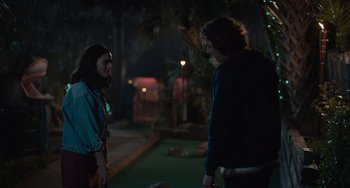 Movie still from “Along for the Ride” (2022), directed by Sofia Alvarez – Two men standing next to each other in a dark room; Medium shot, Over the shoulder angle