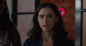 Movie still from “Along for the Ride” (2022), directed by Sofia Alvarez – A woman with long black hair wearing a blue shirt; Close Up shot, Over the shoulder angle