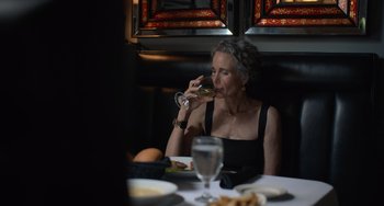 Movie still from “Along for the Ride” (2022), directed by Sofia Alvarez – An older woman sitting at a dinner table drinking wine; Close Up shot, Over the shoulder angle