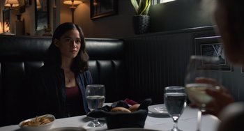 Movie still from “Along for the Ride” (2022), directed by Sofia Alvarez – A woman sitting at a table in front of a bowl of food; Medium shot, Over the shoulder angle