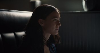 Movie still from “Along for the Ride” (2022), directed by Sofia Alvarez – A woman sitting in a chair looking to her left; Close Up shot, Over the shoulder angle