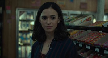 Movie still from “Along for the Ride” (2022), directed by Sofia Alvarez – A woman standing next to a store shelf in a store; Close Up shot, Over the shoulder angle