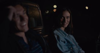 Movie still from “Along for the Ride” (2022), directed by Sofia Alvarez – A woman sitting in the back seat of a car at night; Close Up shot, Over the shoulder angle