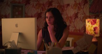 Movie still from “Along for the Ride” (2022), directed by Sofia Alvarez – A woman sitting in front of a computer monitor; Medium shot, High angle