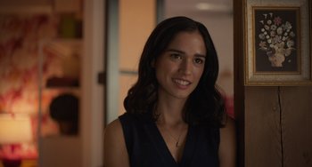 Movie still from “Along for the Ride” (2022), directed by Sofia Alvarez – A woman in a black top smiling for the camera; Close Up shot, Over the shoulder angle
