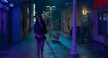 Movie still from “Along for the Ride” (2022), directed by Sofia Alvarez – A woman walking down a street at night; Wide shot, Low angle