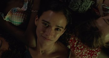 Movie still from “Along for the Ride” (2022), directed by Sofia Alvarez – A young woman's face in the dark; Close Up shot, High angle