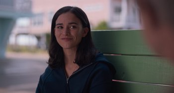 Movie still from “Along for the Ride” (2022), directed by Sofia Alvarez – A woman sitting on top of a wooden bench outside; Close Up shot, Over the shoulder angle