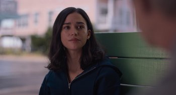 Movie still from “Along for the Ride” (2022), directed by Sofia Alvarez – A woman sitting on top of a wooden bench outside; Close Up shot, Over the shoulder angle