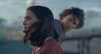 Movie still from “Along for the Ride” (2022), directed by Sofia Alvarez – A woman and a man standing next to each other; Close Up shot, Over the shoulder angle