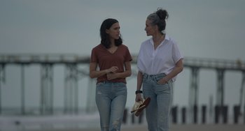 Movie still from “Along for the Ride” (2022), directed by Sofia Alvarez – Two women are walking on the beach talking to each other; Medium shot, Over the shoulder angle