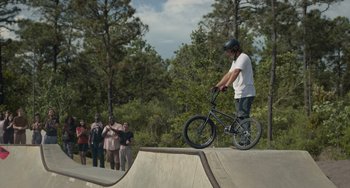 Movie still from “Along for the Ride” (2022), directed by Sofia Alvarez – A man riding a bike on top of a ramp; Wide shot, Over the shoulder angle