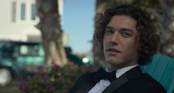 Movie still from “Along for the Ride” (2022), directed by Sofia Alvarez – A man in a suit and bow tie; Close Up shot, Low angle