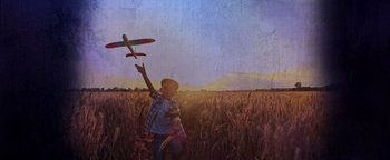 Movie still from “American Carnage” (2022), directed by Diego Hallivis – A man flying a toy airplane in a field; Extreme Close Up shot, Low angle