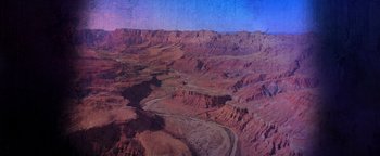 Movie still from “American Carnage” (2022), directed by Diego Hallivis – An aerial view of a valley with a river running through it; Extreme Wide shot, High angle