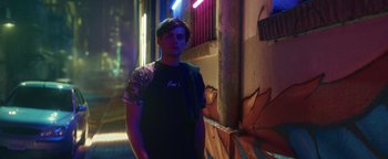 Movie still from “American Carnage” (2022), directed by Diego Hallivis – A young man standing in a dark alley; Medium shot, Low angle