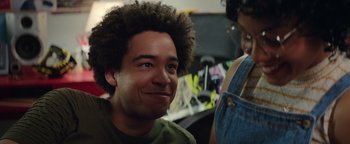 Movie still from “American Carnage” (2022), directed by Diego Hallivis – A young man with blue eyes smiling at the camera; Close Up shot, Over the shoulder angle