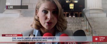 Movie still from “American Carnage” (2022), directed by Diego Hallivis – A woman is talking to the press with a microphone; Close Up shot, Low angle