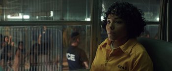 Movie still from “American Carnage” (2022), directed by Diego Hallivis – A man standing in front of a window with another man in the background; Close Up shot, Over the shoulder angle