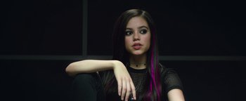 Movie still from “American Carnage” (2022), directed by Diego Hallivis – A woman with purple hair sitting in front of a black wall; Close Up shot, Over the shoulder angle