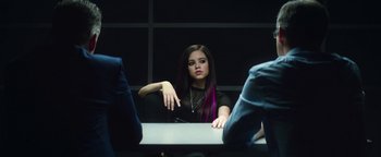 Movie still from “American Carnage” (2022), directed by Diego Hallivis – A woman sitting at a table in front of two other people; Medium shot, Over the shoulder angle