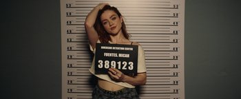 Movie still from “American Carnage” (2022), directed by Diego Hallivis – A woman holding up a sign in front of a police wall; Medium shot, Low angle