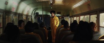 Movie still from “American Carnage” (2022), directed by Diego Hallivis – A man standing on a bus in a room with many people; Wide shot, Low angle