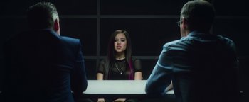 Movie still from “American Carnage” (2022), directed by Diego Hallivis – A woman with purple hair sitting at a table; Medium shot, Over the shoulder angle