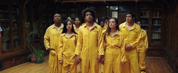 Movie still from “American Carnage” (2022), directed by Diego Hallivis – A group of young people in yellow jumpsuits standing together; Medium shot, Low angle