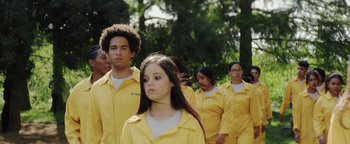 Movie still from “American Carnage” (2022), directed by Diego Hallivis – A group of young people in yellow jackets walking; Medium shot, Over the shoulder angle