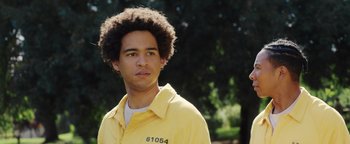 Movie still from “American Carnage” (2022), directed by Diego Hallivis – A young man in a yellow prison uniform; Close Up shot, Low angle