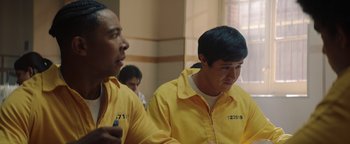 Movie still from “American Carnage” (2022), directed by Diego Hallivis – A couple of men in yellow jackets sitting next to each other in a room; Medium shot, Over the shoulder angle