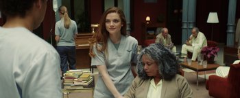 Movie still from “American Carnage” (2022), directed by Diego Hallivis – A woman standing next to another woman in a room; Medium shot, Over the shoulder angle