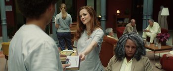 Movie still from “American Carnage” (2022), directed by Diego Hallivis – A woman in a white lab coat holding a book; Medium shot, Over the shoulder angle