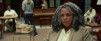 Movie still from “American Carnage” (2022), directed by Diego Hallivis – An older woman sitting in front of a piano; Close Up shot, Over the shoulder angle