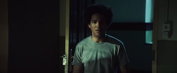 Movie still from “American Carnage” (2022), directed by Diego Hallivis – A young man standing in a dark room; Close Up shot, Low angle