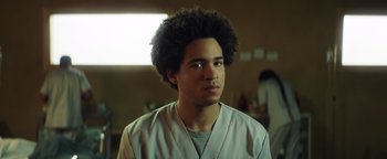 Movie still from “American Carnage” (2022), directed by Diego Hallivis – A young man with a black afro is looking at the camera; Close Up shot, Low angle