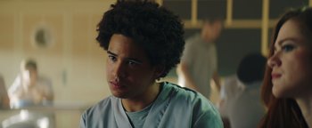 Movie still from “American Carnage” (2022), directed by Diego Hallivis – A young man with a curly afro is looking into the distance; Close Up shot, Low angle