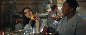 Movie still from “American Carnage” (2022), directed by Diego Hallivis – A group of people sitting at a table eating food; Medium shot, Over the shoulder angle