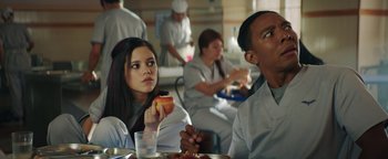 Movie still from “American Carnage” (2022), directed by Diego Hallivis – A group of people sitting at a table eating food; Medium shot, Over the shoulder angle