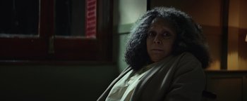Movie still from “American Carnage” (2022), directed by Diego Hallivis – An older woman sitting in front of a window; Close Up shot, Over the shoulder angle