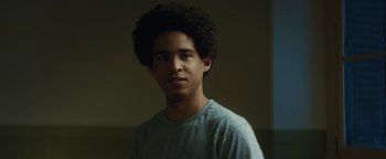 Movie still from “American Carnage” (2022), directed by Diego Hallivis – A young man with a black afro is posing for a picture; Close Up shot, Low angle