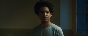 Movie still from “American Carnage” (2022), directed by Diego Hallivis – A young man with a very large afro is posing for a picture; Close Up shot, Low angle