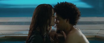 Movie still from “American Carnage” (2022), directed by Diego Hallivis – A man and a woman kissing in a room; Medium shot, Low angle