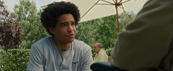 Movie still from “American Carnage” (2022), directed by Diego Hallivis – A young man sitting under an open umbrella; Close Up shot, Low angle