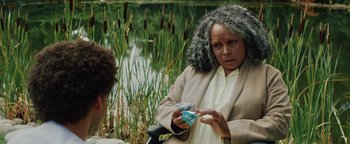 Movie still from “American Carnage” (2022), directed by Diego Hallivis – An older woman is holding something in her hand; Close Up shot, Over the shoulder angle