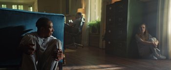 Movie still from “American Carnage” (2022), directed by Diego Hallivis – A man sitting in a chair in front of a window; Medium shot, Low angle