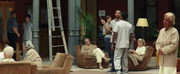 Movie still from “American Carnage” (2022), directed by Diego Hallivis – A group of people standing in a living room; Wide shot, Over the shoulder angle