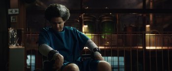 Movie still from “American Carnage” (2022), directed by Diego Hallivis – A man sitting on top of a chair in a room; Medium shot, Low angle